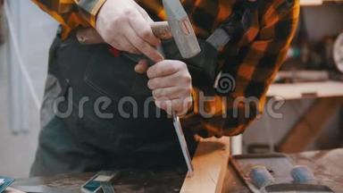 室内<strong>木工</strong>-一名<strong>木工用</strong>凿子和锤子在木块上做缺口
